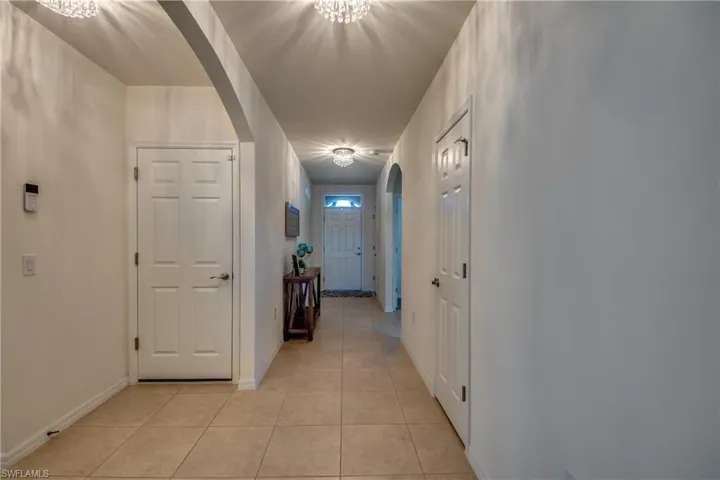 Hall featuring a notable chandelier and light tile flooring