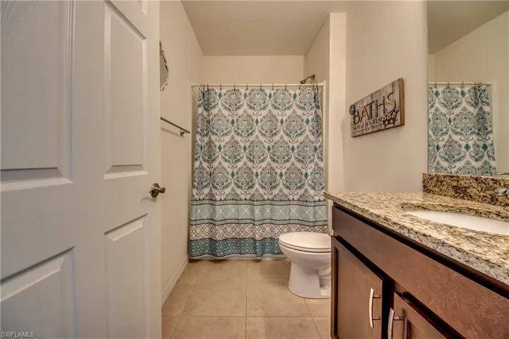 Bathroom with tile flooring, toilet, and vanity with extensive cabinet space