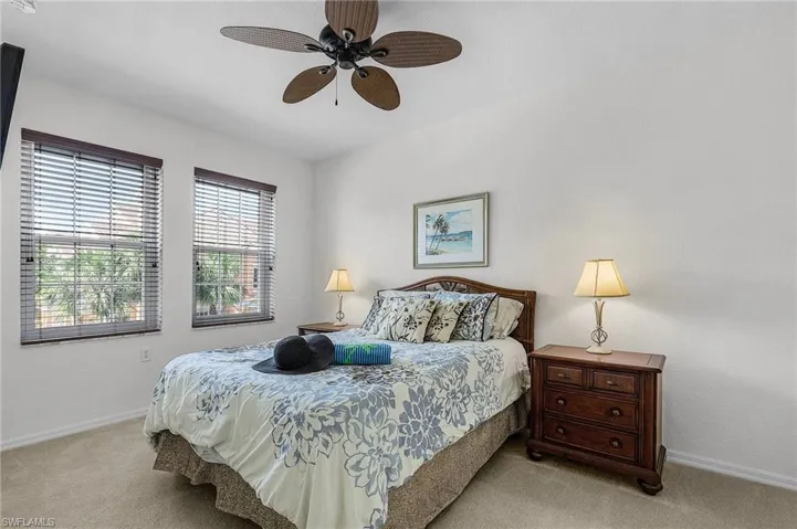 Carpeted bedroom with ceiling fan and baseboards