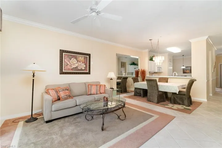 Living area featuring crown molding, light tile patterned floors, and a ceiling fan.