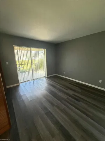 Spare room with dark wood-style flooring and baseboards