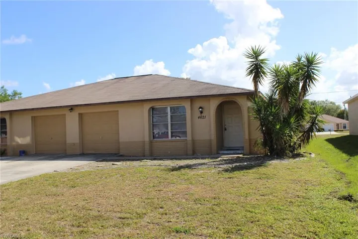Ranch-style house featuring a front yard, stucco siding, driveway, and an attached garage