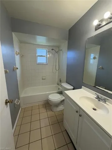Full bath with vanity, light tile patterned flooring, and tub / shower combination