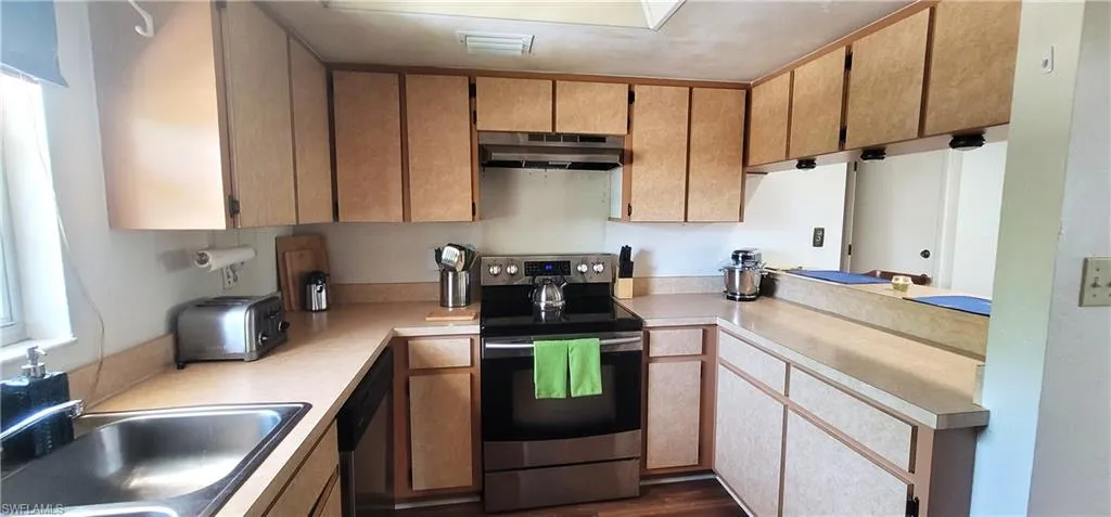 Kitchen featuring appliances with stainless steel finishes, under cabinet range hood, and light countertops