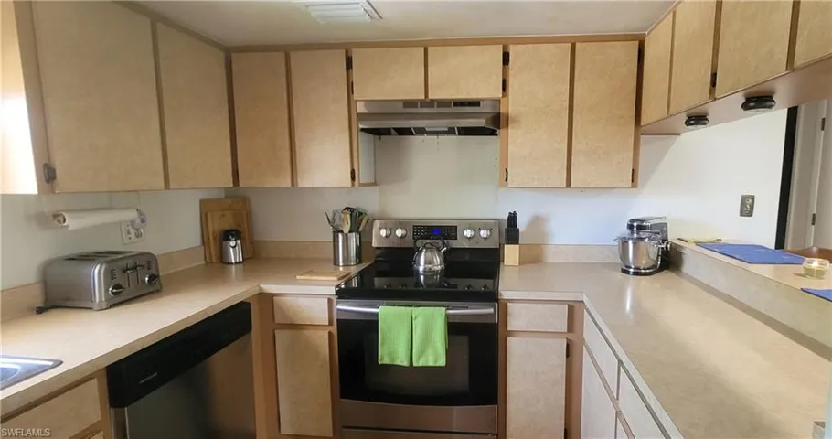Kitchen with appliances with stainless steel finishes, under cabinet range hood, and light countertops