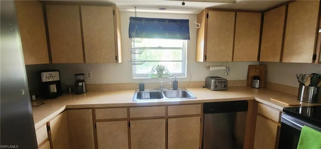 Kitchen with stainless steel dishwasher, light countertops, and black electric range oven