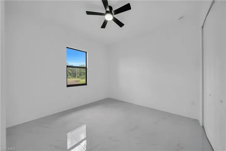 Spare room with marble look tiles and ceiling fan