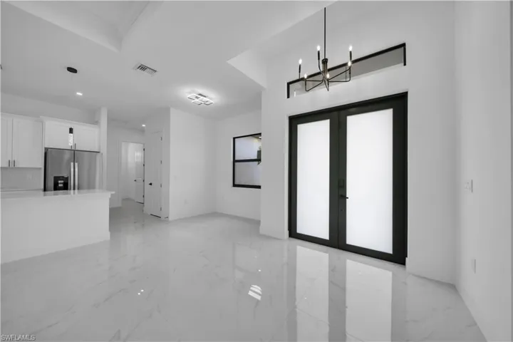 Unfurnished living room with french doors, light marble finish floors, a chandelier, and recessed lighting