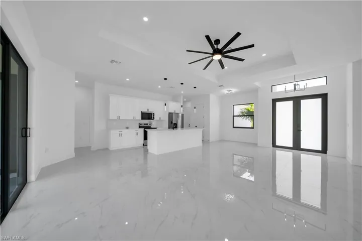 Unfurnished living room featuring a raised ceiling, recessed lighting, french doors, light marble finish flooring, and ceiling fan