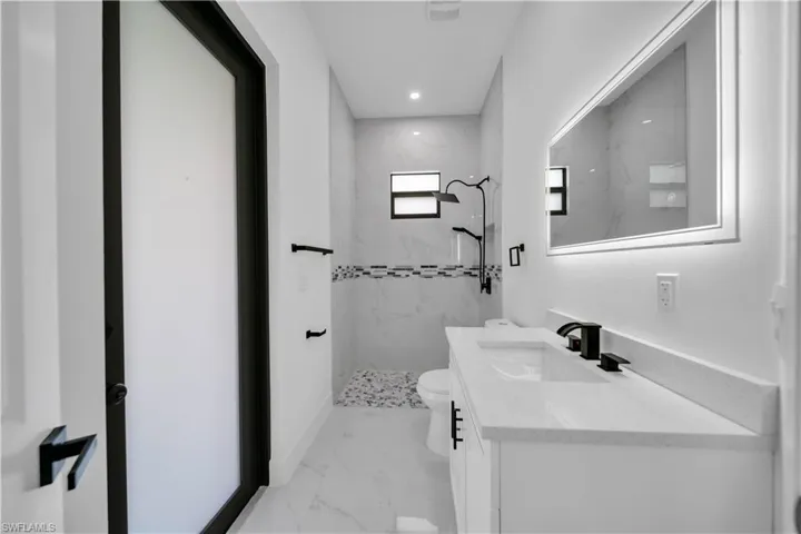 Bathroom featuring marble look tile flooring, vanity, a marble finish shower, and recessed lighting