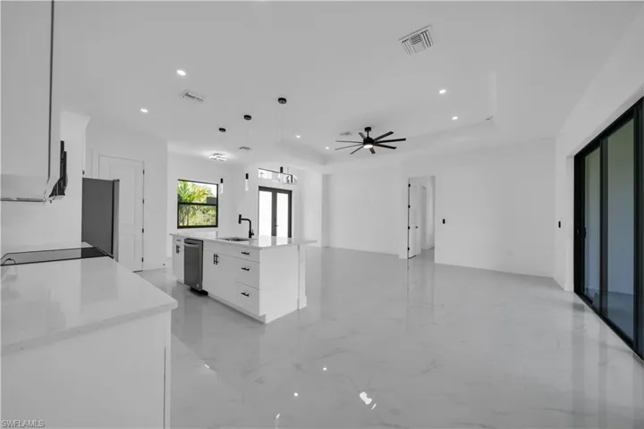 Kitchen featuring recessed lighting, open floor plan, white cabinets, a kitchen island with sink, and pendant lighting