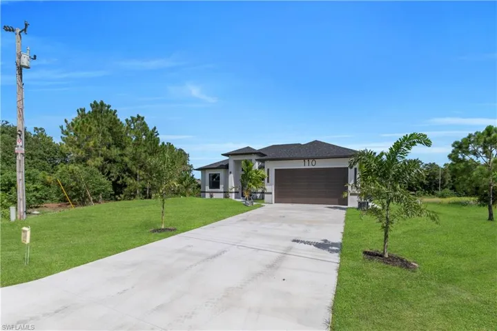 Prairie-style house with an attached garage, a front yard, driveway, and stucco siding