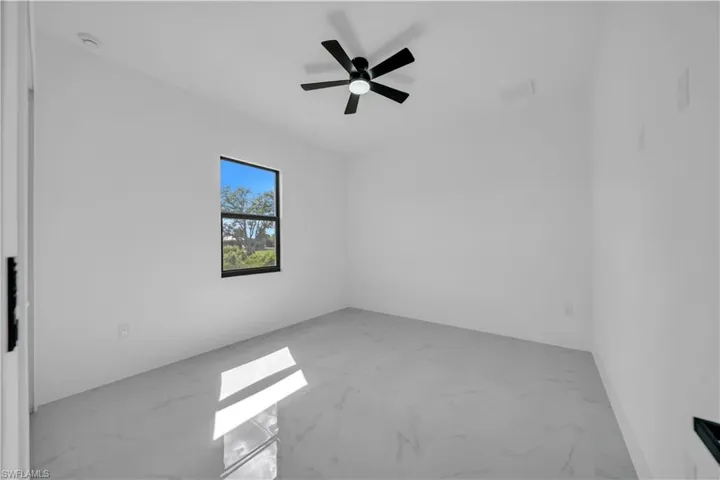 Empty room with marble look tiles and ceiling fan