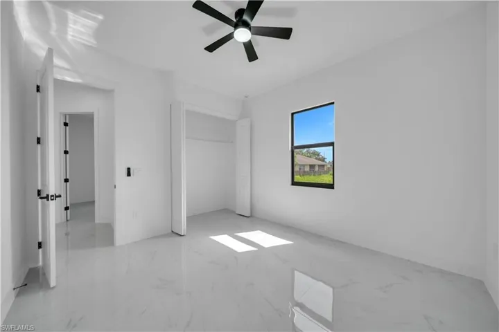 Unfurnished bedroom with marble finish floors, a ceiling fan, and a closet