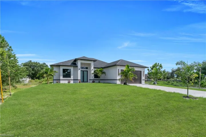 Prairie-style house with concrete driveway, a garage, stucco siding, and a front yard