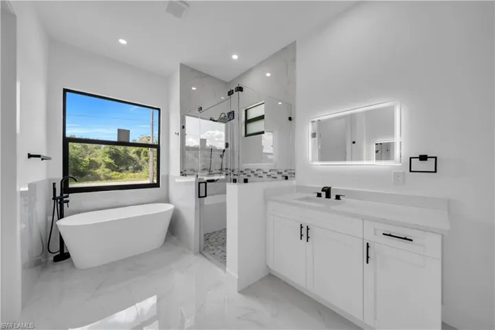 Bathroom with a marble finish shower, a freestanding tub, vanity, marble tiled flooring, and recessed lighting
