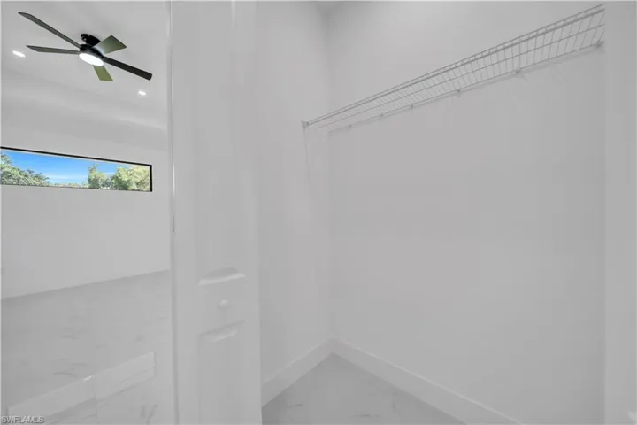 Spacious closet with marble finish flooring and ceiling fan