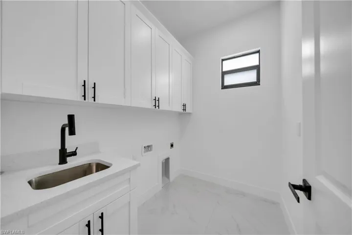 Laundry room with cabinet space, hookup for an electric dryer, light marble finish floors, and washer hookup
