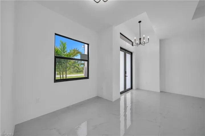 Spare room featuring marble finish floors and a chandelier