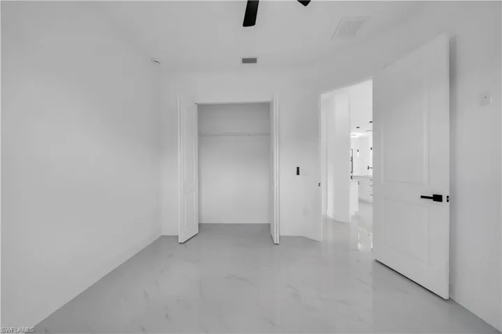 Unfurnished bedroom with light marble finish flooring, a closet, and ceiling fan