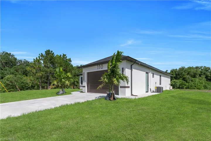 View of home's exterior with stucco siding, a lawn, driveway, and an attached garage