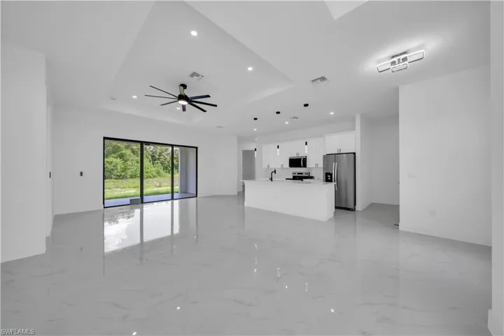 Unfurnished living room featuring light marble finish floors, recessed lighting, a raised ceiling, and ceiling fan