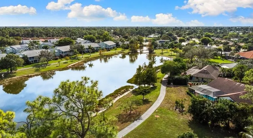 Aerial perspective of suburban area featuring a large body of water and a tree filled landscape