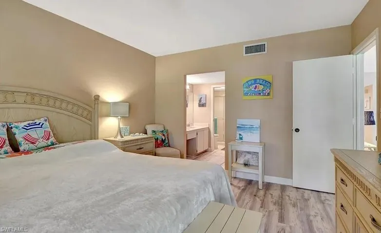 Bedroom with light wood-style floors and connected bathroom