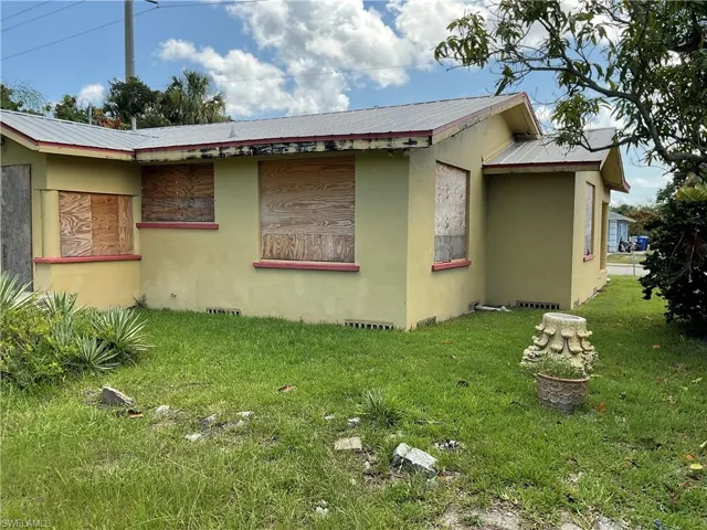 View of side of home featuring stucco siding, a lawn, and a metal roof