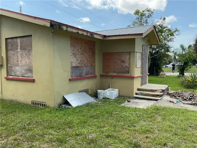 View of side of home with stucco siding, a yard, and a metal roof