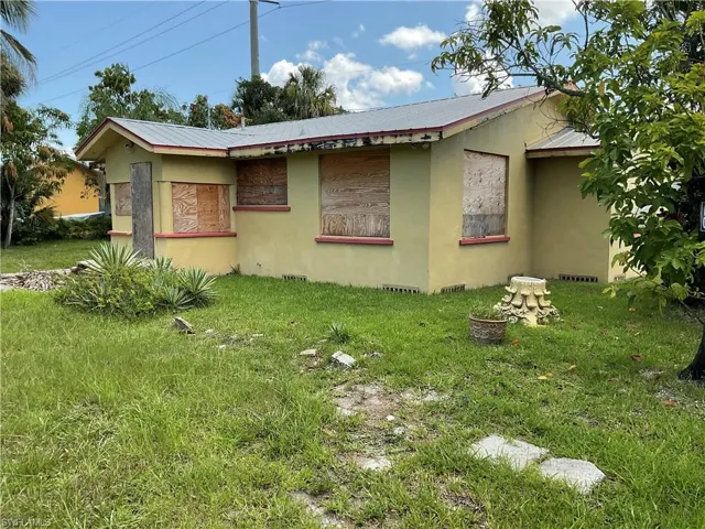 View of side of home with a metal roof, stucco siding, and a yard
