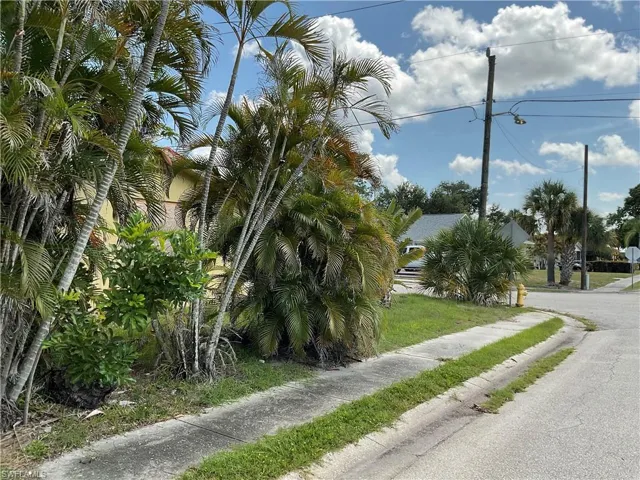 View of asphalt road featuring sidewalks, street lighting, and curbs