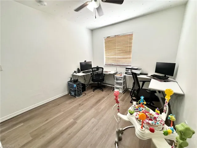 Office area with wood finished floors, a ceiling fan, and a textured wall