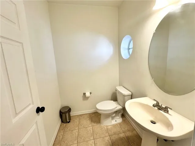 Half bath featuring toilet and light tile patterned flooring