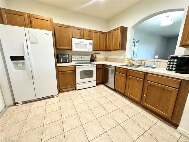 Kitchen with white appliances, light countertops, and wood finish cabinets