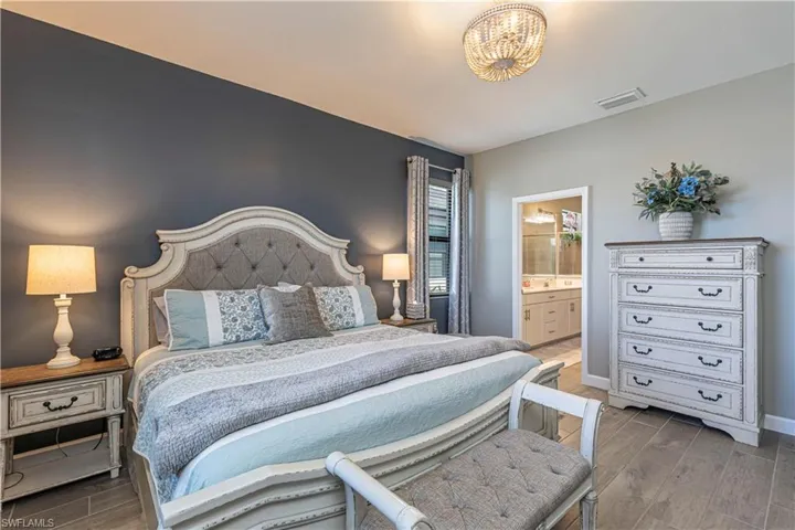 Bedroom featuring baseboards, visible vents, ensuite bathroom, and wood tiled floor
