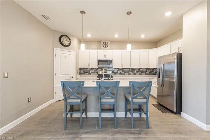 Kitchen featuring tasteful backsplash, visible vents, white cabinets, and stainless steel appliances