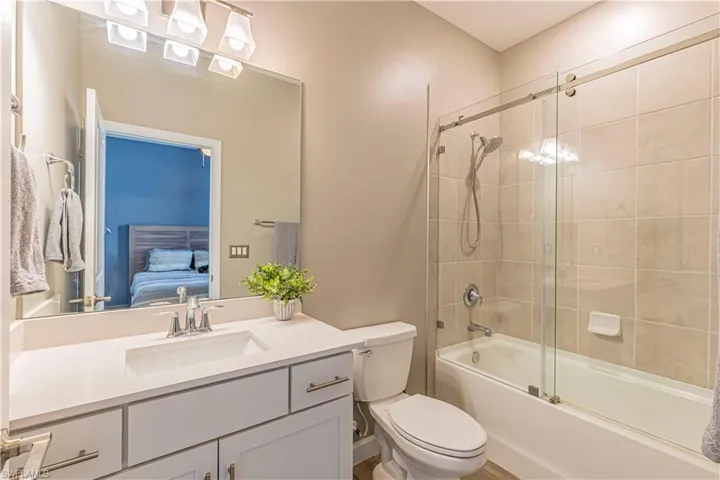 Bathroom with ensuite bathroom, toilet, vanity, and shower / bath combination with glass door