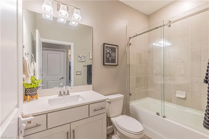 Full bath with shower / bath combination with glass door, vanity, and toilet