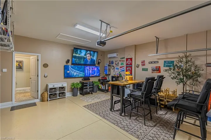 Garage converted to a entertainment space. a wall mounted AC, speckled floor, and a garage