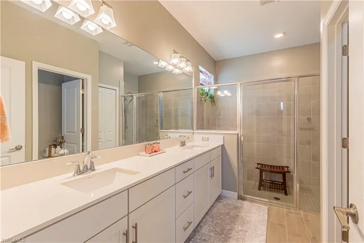 Bathroom featuring double vanity, a shower stall, and a sink
