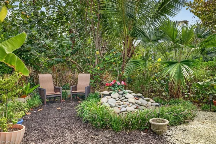 Lush landscaping with diverse plantings, a decorative rock feature, and woodchip ground cover