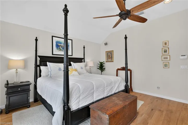 Vaulted ceiling, wood-finish flooring, ceiling fan with integrated lighting, recessed wall-mounted speakers, and light-toned wall finishes