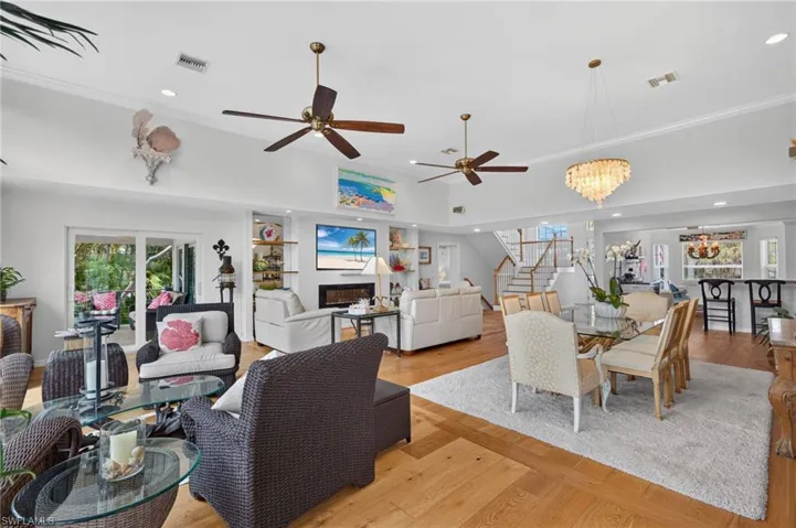 Vaulted ceilings, wood-finish flooring, recessed lighting, ceiling fans, and a chandelier illuminate the living and dining areas