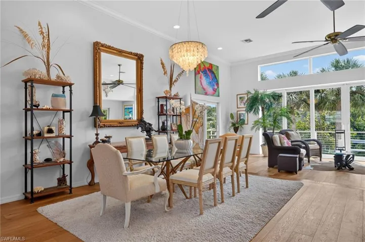 Expansive open-concept living space with wood-finish flooring, high ceilings, and a crystal chandelier