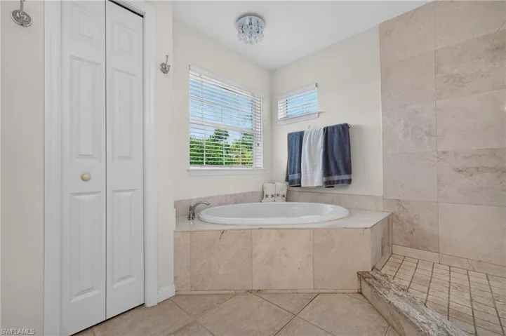 Built-in soaking tub with deck-mounted faucet, tile surround, and adjacent tiled shower