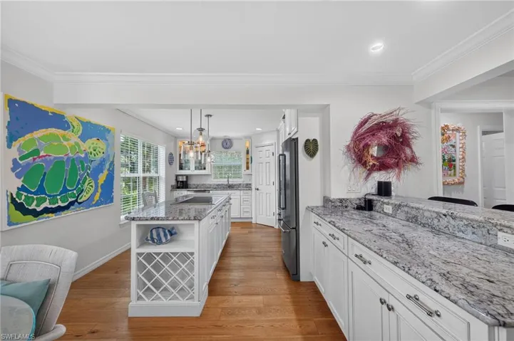 Kitchen featuring a substantial island with built-in wine storage, white cabinetry, and light-toned granite countertops