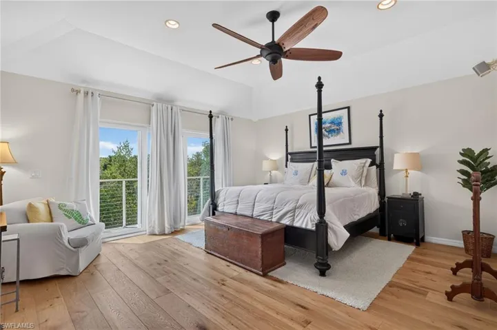 Vaulted ceiling with recessed lighting and a ceiling fan, wood-finish flooring, and multiple glass panel doors providing outdoor access