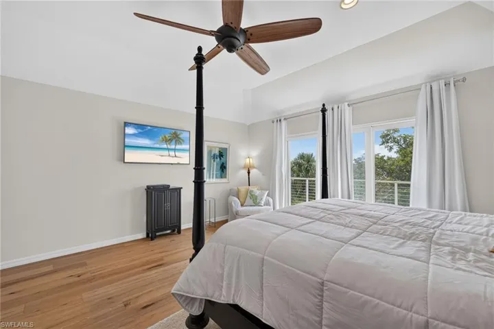 Wood-finish flooring, tray ceiling, and a ceiling fan with wood-tone blades
