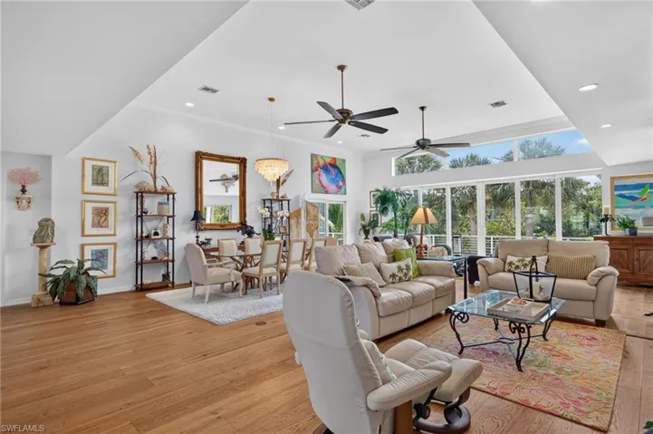 Open-concept living space featuring wood-finish flooring, high vaulted ceilings, and extensive window walls